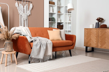 Interior of modern living room with brown sofa, warm blanket and pampas grass