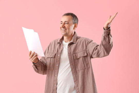 Mature actor with film script on pink background