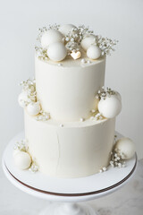 Fototapeta na wymiar Big bunk wedding cake covered with white chocolate frosting and decorated with white chocolate spheres on the white background.