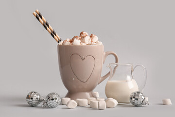 Cup of hot cocoa with marshmallows and Christmas balls on grey background