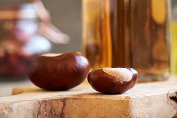Horse chestnuts on a table with a bottle of tincture in the background
