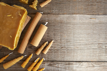 Bees wax candles with a block of wax on a wooden background with copy space