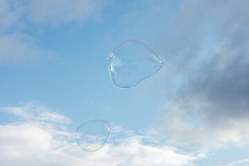 Big soap bubbles fly through the air in front of a blue sky
