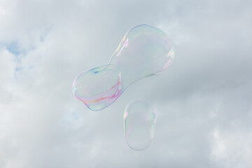 Big soap bubbles fly through the air in front of a blue sky