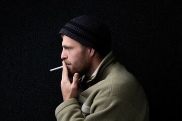 White man hipster or homes studio model smoking cigarets theme, isolated on dark background, fun...