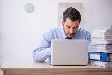 Young male employee and too much work in the office