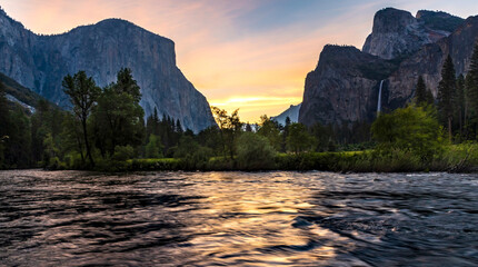 dramatic sunrise in Yosemite National park with the Merced River on the foreground and Bridal Veil Falls and The El Capitan on the background.