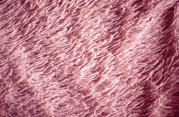 Closeup of a soft fluffy pink textured throw blanket. Fur fuzzy blanket surface