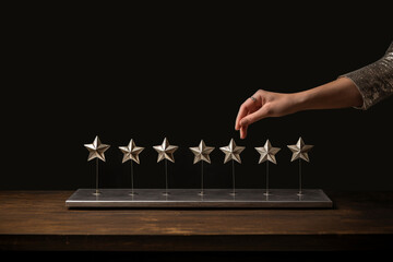 Stars made of metal sitting on a table and a hand touches the star from top, hand touching stars,...