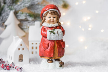 Retro Christmas card with a cute figure of a child on a snowy background. A girl in a red coat warms her hands in a muff. The concept of the winter holiday new year 2024.