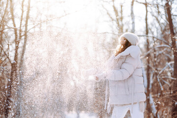 Young woman enjoys the wonderful winter atmosphere in the forest. Woman standing among snowy trees...