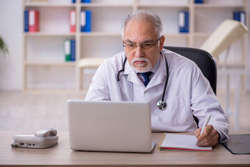 Old male doctor in telemedicine concept