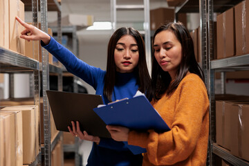 Warehouse worker and supply chain manager tracking inventory in storage room. Storehouse employees...