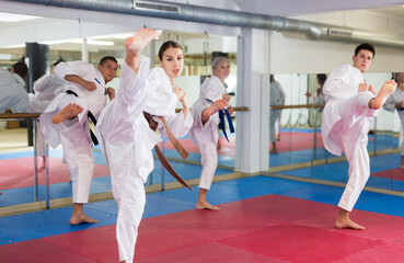 Group of men and women in kimono performing kata in gym during training