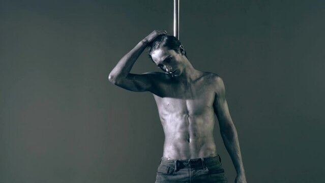 Pole dancer. Guy does gymnastic exercises on pole dance. Pole dancing for slim fitness body. Flexibility. Pole dance. Pylon dancing strength, flexibility, and grace. Strip muscular man dancer.