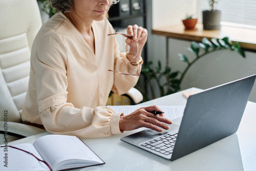Leinwandbilder hand with pen of mature female analyst over laptop keyboard during network or work with online data 
