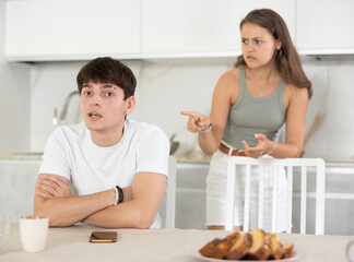 Young woman quarrels with young guy in kitchen at home