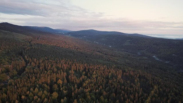 View from above to the hills and mountains in Szklarska Poręba during sunrise. Forests, illuminated by the rising sun trees, in the distance mountains