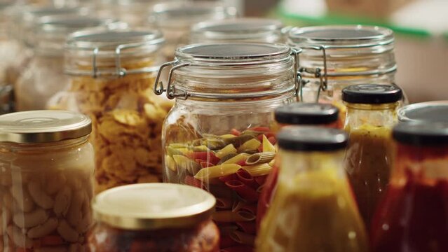 Close up on bulk products in reusable glass jars used by zero waste supermarket to lower climate impact. Local shop pantry staples in decomposable packaging, panning shot