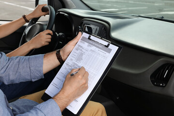Driving school. Student passing driving test with examiner in car at parking lot, closeup
