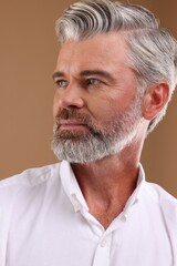 Portrait of confident man with beautiful hairstyle on light brown background