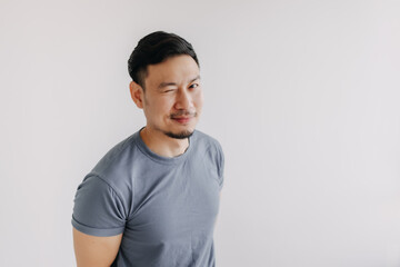 Happy asian man wears blue t-shirt and jeans winking at camera and smile.