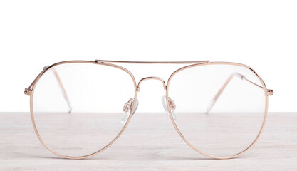 Stylish glasses with metal frame on wooden table against white background