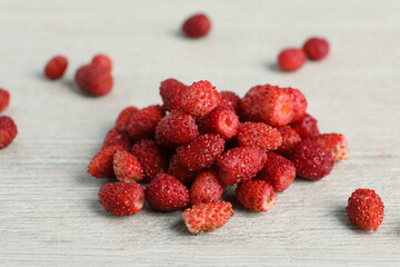 Pile of wild strawberries on white wooden table, closeup