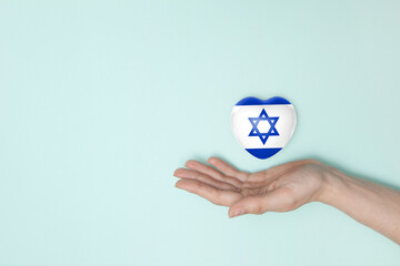 Heart with print of Israel flag in female hands. Flat lay. Copy space.