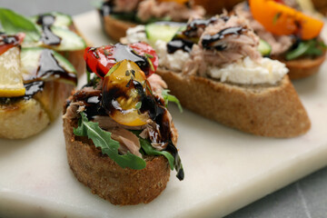 Delicious bruschettas with balsamic vinegar and different toppings on table, closeup