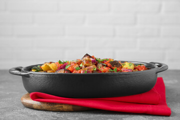 Dish with tasty ratatouille on grey textured table
