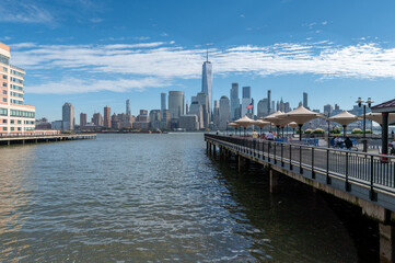 Stunning NYC skyline unfolds from Jersey City Harbour, with iconic skyscrapers reaching for clear skies. The Hudson River reflects the architectural marvels, epitomizing urban beauty across the waters