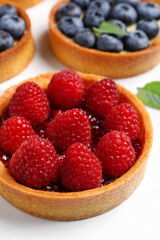 Tartlet with fresh raspberries on white table, closeup. Delicious dessert