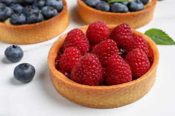 Tartlet with fresh raspberries on white table, closeup. Delicious dessert