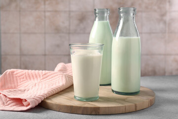 Glassware with tasty milk on light gray table, space for text