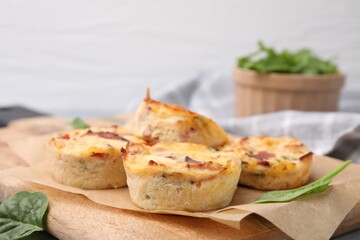 Delicious egg muffins with cheese and bacon on wooden board, closeup. Space for text