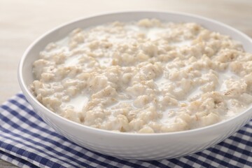 Tasty boiled oatmeal in bowl on table, closeup