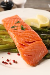Tasty grilled salmon with asparagus and lemon on plate, closeup