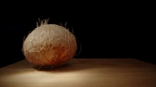 I Place a Whole Hairy Coconut on the Table under Sunrays, Close-Up.