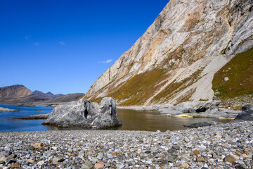 Peaceful rocky beach on a sunny blue sky day on Gnalodden, arctic expedition tourism around...