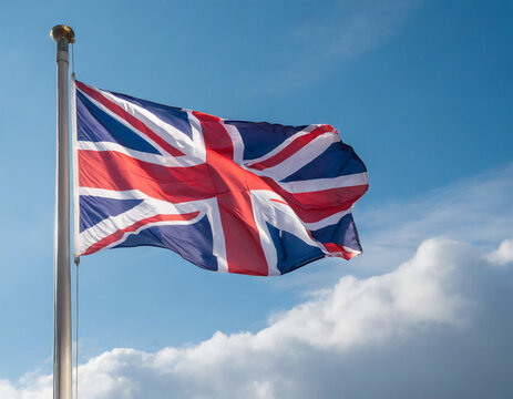 Close up view of an UK flag waving on a flagpole, with blue sky background and copy space