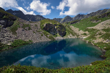 View of the Dukka lake "Rybka" on the Malaya Dukka River on the slopes of the Arkasar ridge in the North Caucasus on a sunny summer day, Arkhyz, Karachay-Cherkessia, Russia © Ula Ulachka