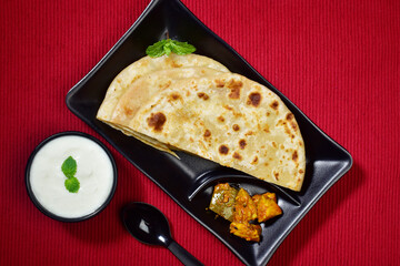 Top view of plain paratha served with dahi and achar