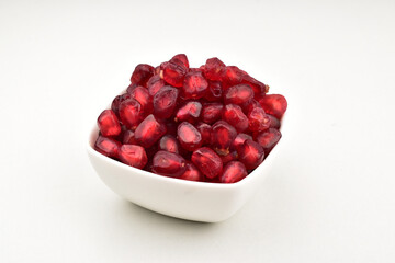 Closeup of pomegranate seeds in bowl isolated on white background