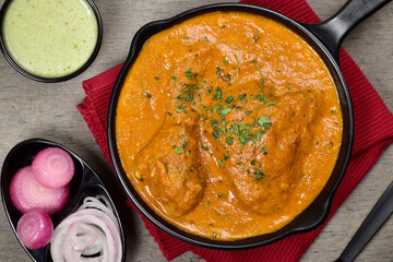 Top view of restaurant style murg makhani served with mint chutney and onion