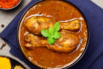 Top view of masala chicken curry in bowl garnished with mint leaves