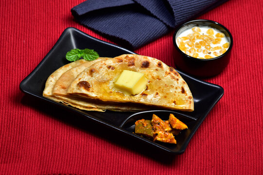 Indian breakfast butter paratha with raita and pickle 