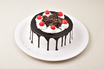 Chocolate vanilla cake with red cherry in plate on white background, whole cake