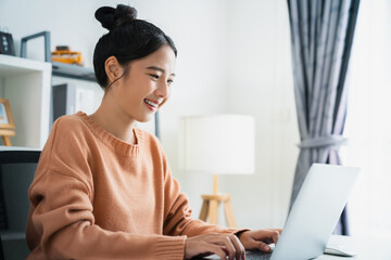 Young attractive female sitting at the desk and using laptop computer.