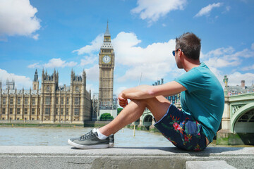 a young men tourist on a city trip in London looking at the Big Ben at Westminster Bridge